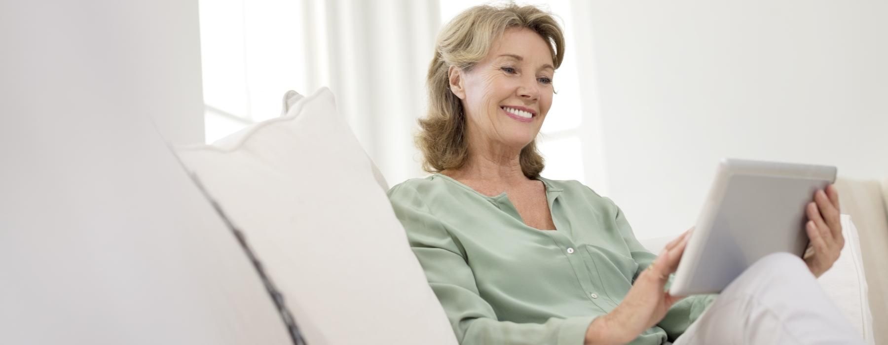 a person sitting on a couch looking at a tablet